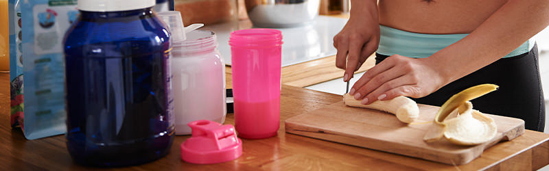 Mulher corta banana para preparar o suplemento vitamínico.